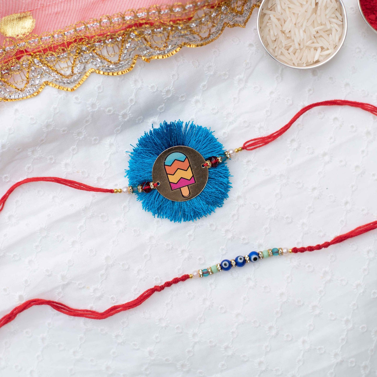 Set of 2 Rakhis, one with a cute metal charm, and another with evil eye beads & macramé detailing - Blue, Red, Yellow